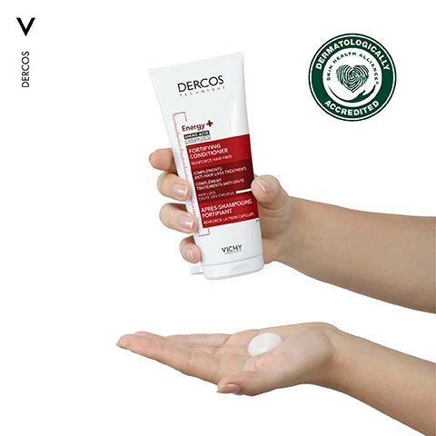 Image 1 - A person is holding a tube of Dercos Fortifying Conditioner with a small amount of the product in the palm of their other hand, and the tubes label includes the text Energy + AMINO ACID CERAMIDES FORTIFYING CONDITIONER and VICHY DERMATOLOGICALLY ACCREDITED.
Image 2 - A close-up portrait of a woman with wavy hair, looking directly at the camera while holding her hair with one hand; the image includes the text COMBATS HAIR LOSS DUE TO BREAKAGE.
Image 3 - Image shows two hair care products for an anti-breakage routine: on the left, a bottle of Dercos Energy Plus Stimulating Shampoo labeled as CLEANSE & ENERGISE and on the right, a tube of Dercos Energy Plus Fortifying Conditioner labeled as NOURISH & STRENGTHEN, with the steps clearly indicated as STEP 1 and STEP 2.