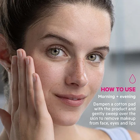 Image 4 - A woman with clear skin gently touches her cheek with her hand while looking directly at the camera, next to text that reads HOW TO USE Morning + evening Dampen a cotton pad with the product and gently sweep over the skin to remove makeup from face, eyes and lips, with a pink drop icon above it.