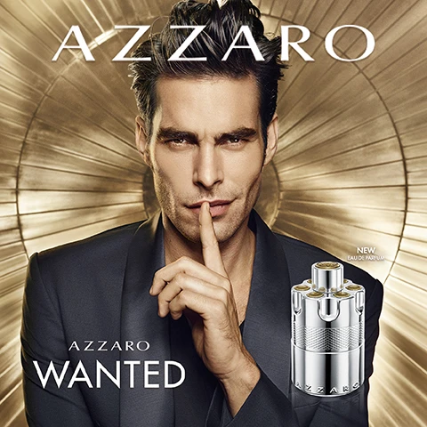 Image 3 - A dark-haired man in a dark suit jacket shushes the viewer with a finger on his lips, next to a silver, revolver-cylinder-shaped perfume bottle with gold accents, against a golden radial background, with text reading AZZARO, AZZARO WANTED, NEW EAU DE PARFUM. Image 4 - A silver perfume bottle shaped like a revolver cylinder with AZZARO on its side, surrounded by juniper berries with green needles, sage leaves, and dry vetiver roots on a reflective surface, with text reading FUSING JUNIPER BERRIES, VIBRANT SAGE, and ELEGANT VETIVER. Image 5 - A sleek silver cylindrical perfume bottle, embossed with AZZARO on its base and featuring a textured band, sits on a shimmering, watery surface against a light blue sky, with text that reads AZZARO WANTED FUSING ENERGISING ELEGANT. Image 6 - A man with dark hair and a beard holds a finger to his lips in a shushing gesture, next to a silver, bullet-cylinder-shaped perfume bottle, against a golden background with radiating lines, with the text AZZARO, SEBASTIÁN YATRA, EAU DE PARFUM, AZZARO, and AZZARO WANTED. Image 7 - A hand holds a silver, revolver-shaped perfume bottle with motion blur against a blue background, displaying the text AZZARO WANTED EAU DE PARFUM A DAILY SHOT OF ADRENALINE. Image 8 - Two metallic silver perfume bottles, shaped like revolver cylinders, stand on a reflective surface against a light blue background, with the larger 100ml bottle on the left and the smaller 50ml bottle on the right, both featuring the brand name AZZARO embossed near their base and the text above reading AZZARO WANTED EAU DE PARFUM. Image 9 - Two silver revolver-shaped perfume bottles, a larger 100 mL and a smaller 50 mL, with their corresponding light grey boxes, stand on a reflective surface against a light blue gradient background, displaying text AZZARO WANTED EAU DE PARFUM, AZZARO, e 100 mL Vaporisateur, and e 50 mL Vaporisateur.
