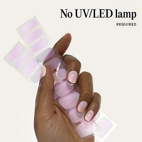Image 1 - A hand holds sheets of light pink pearlescent nail polish strips, with two fingers wearing the same polish, and text says No UV/LED lamp REQUIRED. Image 2 - Two pearlescent light pink and purple press-on nails on a white background 100% real salon-quality gel. Image 3 - Hand with iridescent pink nail polish and text 1 minute removal NO DAMAGE. Image 4 - The image contains illustrations showing four steps for applying and removing nail wraps with the text Step by step 01 PREP Use a Wooden Cuticle Stick to gently push back your cuticles and buff the shine off your nail plates with a 240 grit nail file. Cleanse each nail using a Lint Free Wipe soaked in Prep & Wipe to remove any oils - this helps the wraps adhere better and last longer. If you don’t have these products, washing your hands is a good alternative. If your nails are naturally oily, apply Nail Dehydrator as an extra step after cleansing. 02 STICK & WRAP Choose your favourite design and select the right width wrap for each nail - if you’re between sizes, go slightly smaller. Peel the wrap from the sheet, touching only the end that won’t go on the nail. Apply the wrap as close to the cuticle as possible without touching the skin. Press the wrap firmly from the centre outwards to avoid air bubbles. Use your thumb to press down and seal the edges. 03 TRIM & FILE Trim any excess as close to your nail length as possible using Curved Edged Scissors. After trimming, press the wrap firmly over the free edge of the nail, then file in only one direction, from top to bottom, using a 180 grit nail file. Lightly file underneath the free edge to remove excess and align the edges. Finish by pressing down again to fully seal the wrap in place. Avoid applying any oils or getting your hands wet for at least 2 hours after application to ensure maximum adhesion. Then you’re set for up to 14 days! 04 REMOVE Quick, damage-free removal in just 1 minute. Apply Mylee Wrap Remover Oil around the edges of the wrap. Gently lift one side with a Wooden Cuticle Stick and slowly slide it underneath, adding more oil as needed. Once removed, wipe your nails and wash your hands. Image 5 - A list of product features is shown next to three red nail wraps on a clear backing: Easiest and gentlest mani in the world Lasts up to 14 days Fast & gentle 1-min removal Fully-cured - No LED Lamp required Comes in 10 sizes Long-lasting shine and chip-resistant Quick and easy application Hema-free, vegan, and cruelty-free Pre-cut and ready to go!