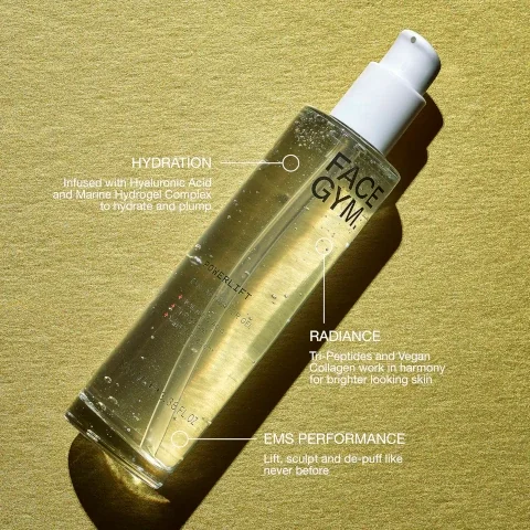 A clear bottle of cosmetic gel with a white pump, labeled FACE GYM. POWERLIFT EMS ACTIVATOR GEL + Hyaluronic Acid + Tri-Peptides + Vegan Collagen* 100 ML e 3.38 FL.OZ, lies on a gold background with text annotations HYDRATION Infused with Hyaluronic Acid and Marine Hydrogel Complex to hydrate and plump, RADIANCE Tri-Peptides and Vegan Collagen work in harmony for brighter looking skin, and EMS PERFORMANCE Lift, sculpt and de-puff like never before.