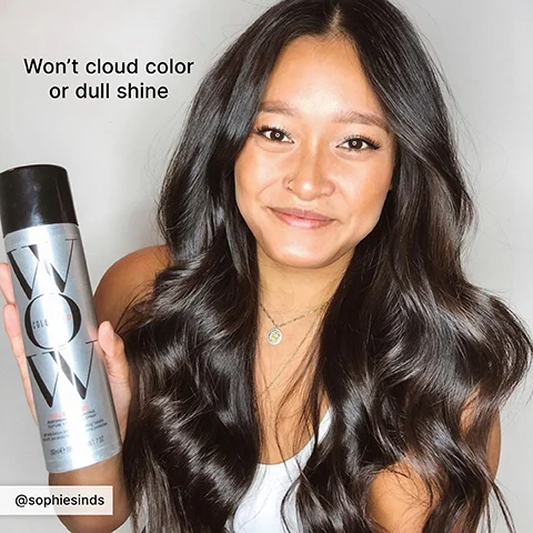 A smiling woman with long, dark, wavy hair holds a silver and black WOW Color Dream Cocktail spray can, with visible text reading Wont cloud color or dull shine and @sophiesinds.