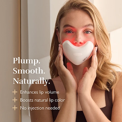 Image 1 - A woman holds a white heart-shaped device emitting red light to her lips with the text Plump. Smooth. Naturally. + Enhances lip volume + Boosts natural lip color + No injection needed Silkn.
Image 2 - A hand holds a pink heart-shaped light therapy device with lights and text reads Effortless rejuvenation + Stimulates collagen + Enhances elastin + Boost microcirculation.
Image 3 - Close-up of a mouth with a finger touching the lower lip, overlaid with text reading 5 minute session time and Results in just 2 weeks.
Image 4 - Two pink LED facial devices on a marble surface, one showing lit bulbs and the other closed, with the text Next level LED Technology 120 LED lights bulbs Wavelengths between 605nm - 1072nm Irradiance between 27.0 - 40.2 mW/cm².
Image 5 - A woman holds a pink heart-shaped LED light therapy device near her face and shoulder with text stating Volume, firmness & anti-ageing + Stimulates collagen + Boosts elastin + Rejuvenates lips & surrounding skin.
Image 6 - Close up of two women with healthy glowing skin overlapping faces, with text Even skin tone & soothing glow + Reduces pigmentation & redness + Boosts microcirculation.