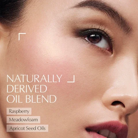 A close up view of a persons face showing the eye, cheek, nose, and mouth with text NATURALLY DERIVED OIL BLEND Raspberry Meadowfoam Apricot Seed Oils.