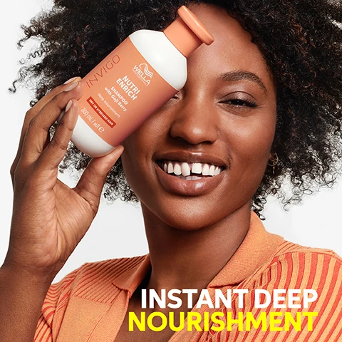 Image 1 - A smiling woman with curly hair holds an orange and white Wella Invigo Nutri-Enrich shampoo bottle near her face, with the text INSTANT DEEP NOURISHMENT visible below, and the bottle text reading INVIGO WELLA PROFESSIONALS NUTRI ENRICH SHAMPOO with Goji Berry deep nourishment DRY OR STRESSED HAIR 300 mL / мл е. Image 2 - A hand squeezes white shampoo from an orange bottle into an open palm, with three white icons and text on the left. The visible text on the left reads DEEP NOURISHMENT, SMOOTHNESS, SOFTNESS, and the bottle displays WELLA PROFESSIONALS INVIGO NUTRI ENRICH SHAMPOO with Goji Berry deep nourishment DRY OR STRESSED HAIR 300 mL / MЛ e. Image 3 - A hand squeezes white product from a salmon-colored tube on a textured orange background, with four white icons on the left illustrating product benefits: two water droplets, three wavy lines, a hand holding strands, and crossed-out wavy lines, accompanying the text Deep Nourishment, Smoothness, Softness, and Anti-Frizz, with the faint numbers 20 visible on the tube. Image 4 - A persons hands hold an open jar of Wella Professionals Invigo Nutri Enrich Mask with Goji Berry for Dry or Stressed Hair, 150 ML, against an orange background, with icons and text listing benefits: Deep Nourishment, Smoothness, Softness, Anti-Frizz. Image 5 - A split image shows a persons hair from behind, with the left side being frizzy and unkempt, labeled BEFORE with non-conditioning shampoo, and the right side being smooth, shiny, and wavy, labeled NUTRI ENRICH with Nutri-Enrich shampoo, mask, Wonder Balm and blow dry. Image 6 - Five red goji berries with green stems are scattered on a white background, with the text Goji Berry, Extremely Rich in Vitamins, Minerals and Peptides.