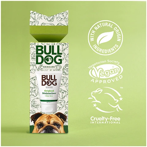 Image 1 - A Bulldog Skincare box and tube of Original Moisturiser are shown with logos stating WITH NATURAL ORIGIN INGREDIENTS, Vegetarian Society Vegan APPROVED, and Cruelty-Free INTERNATIONAL on a green background. Image 2 - A tube of Bulldog Original Moisturiser + Aloe Vera with the text BULLDOG SKINCARE Original Moisturiser + Aloe Vera 100 ml e on the tube, and additional text Moisturiser 24 Hour Hydration and Gift Set Includes in the image. Image 3 - A hand squeezes Bulldog Original Moisturiser from a tube onto another hand showing the text BULL DOG SKINCARE Original Moisturiser + Aloe Vera 24hr Hydration 96% Natural Origin Recycled 100 ml e and Normal To Dry Skin. Image 4 - An open Bulldog Skincare gift box featuring a tube of Original Moisturiser and a bulldog face on the box, placed on a green background with ribbon, and the text #ProtestPointlessGifts.