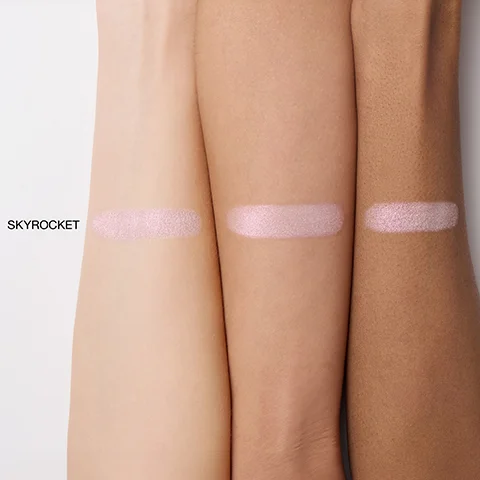 Three arms with fair, medium, and deep skin tones are shown with horizontal swatches of shimmery pale pink product, labeled SKYROCKET.