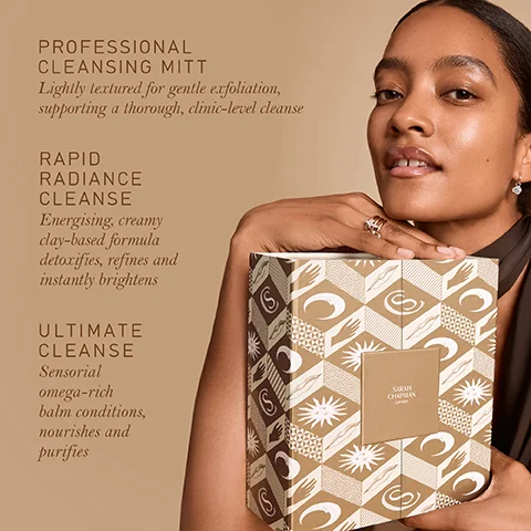 A woman with dark skin holds a decorative patterned box featuring a Sarah Chapman London label, looking towards the viewer, with product descriptions on the left reading: PROFESSIONAL CLEANSING MITT Lightly textured for gentle exfoliation, supporting a thorough, clinic-level cleanse; RAPID RADIANCE CLEANSE Energising, creamy clay-based formula detoxifies, refines and instantly brightens; ULTIMATE CLEANSE Sensorial omega-rich balm conditions, nourishes and purifies.